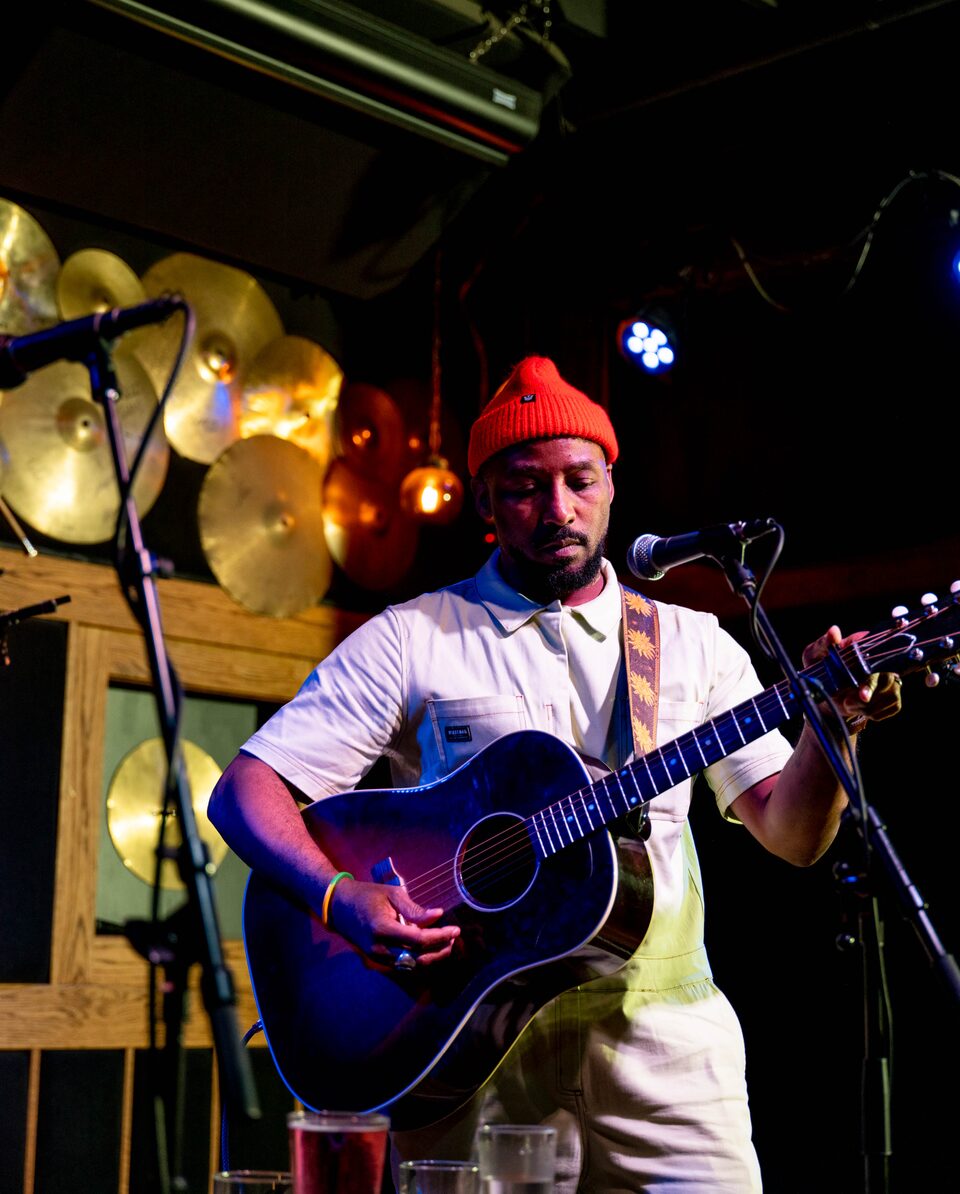 Redray Frazier plays a guitar as he stands in front of a microphone in his studio.
