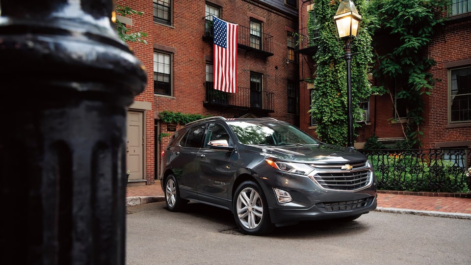 A Chevrolet Equinox parked near a brick building and an American flag.
