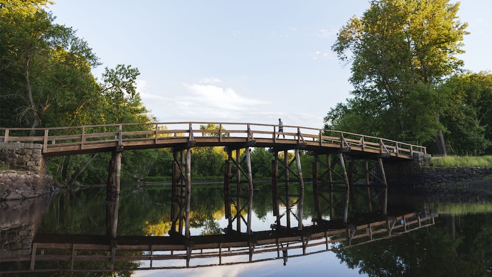 A man walking across Historic North Bridge over the Concord River.