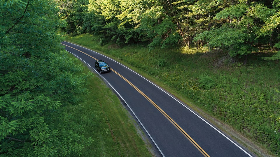 A faraway overhead shot of an Equinox on a two-lane road.