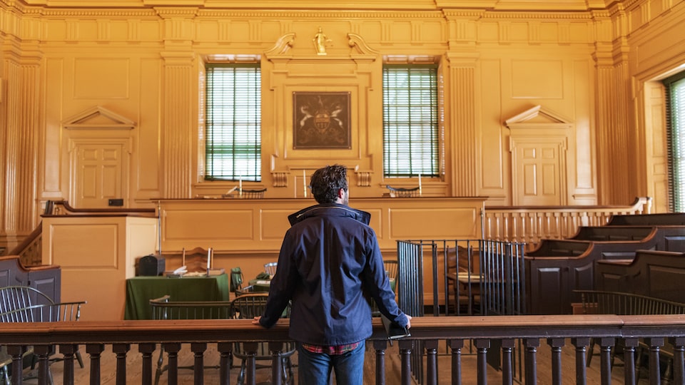 A man stands with his back to the camera inside Independence Hall.