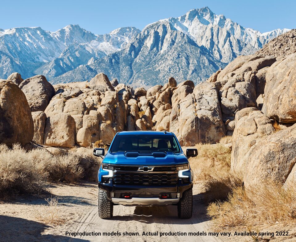 Una Silverado ZR2 azul vista desde el frente en un camino de tierra sinuoso con grandes bloques de roca a los costados.