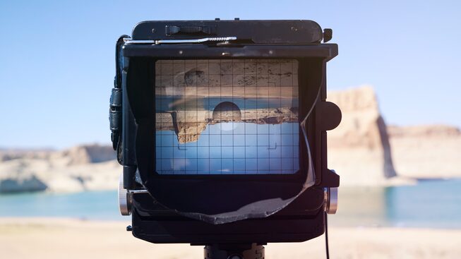 A rock formation is seen upside- down through the lens of a large-format camera.