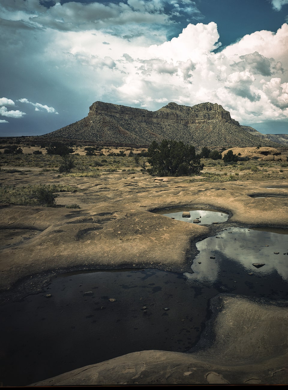 A rock formation is silhouetted against bright clouds and deep blue sky at Toroweap Area in Grand Canyon National Park.