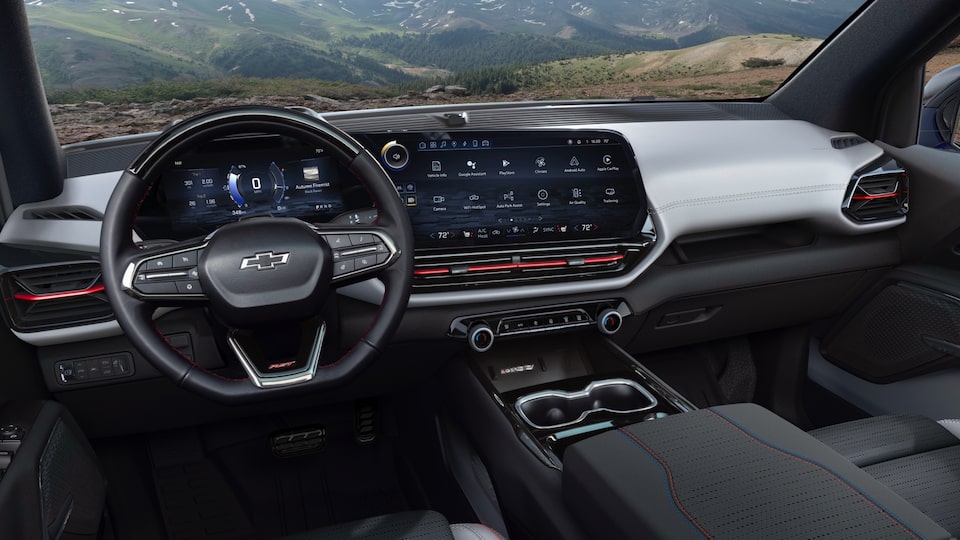 Vista de asiento delantero de una Silverado EV, tomada desde el asiento trasero y con el foco puesto en el volante y los controles del conductor.