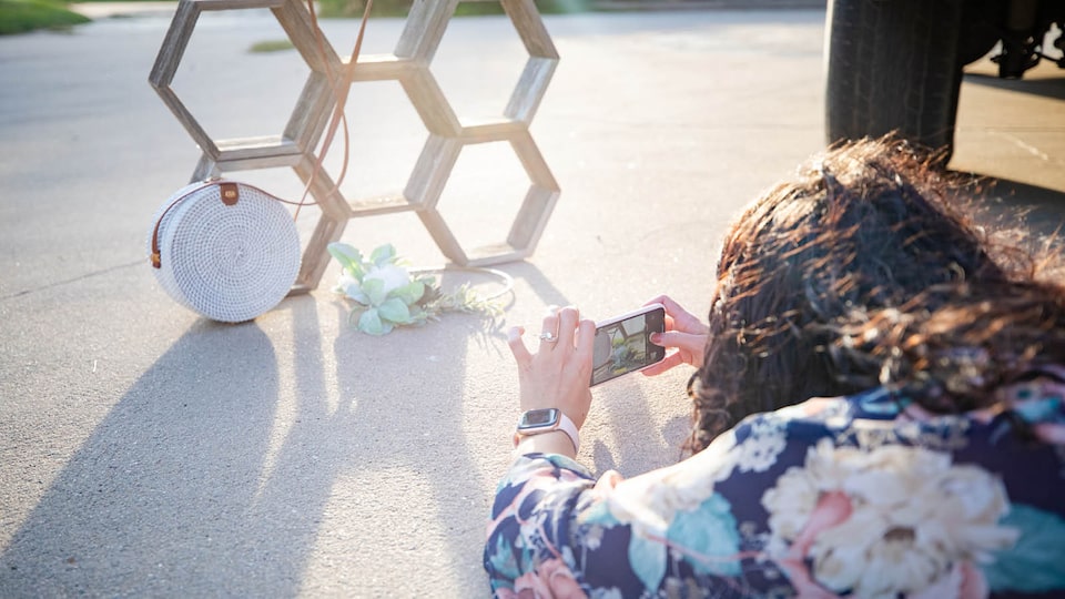 Courtney McLachlan takes a picture of a purse resting against a structure of stacked hexagons.