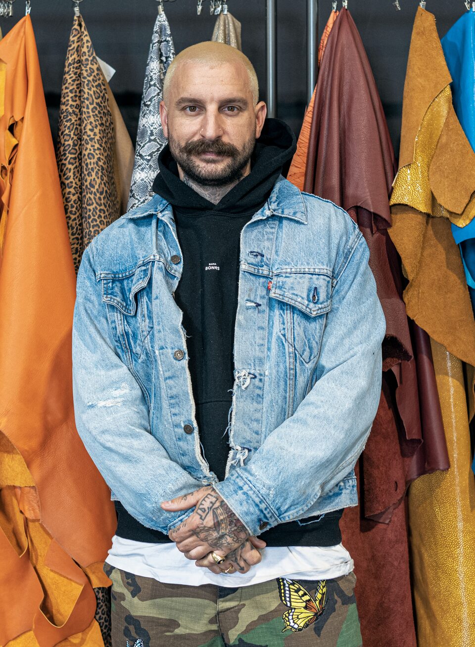 Dominic Ciambrone frente a un exhibidor de piezas de tela que cuelgan de ganchos.