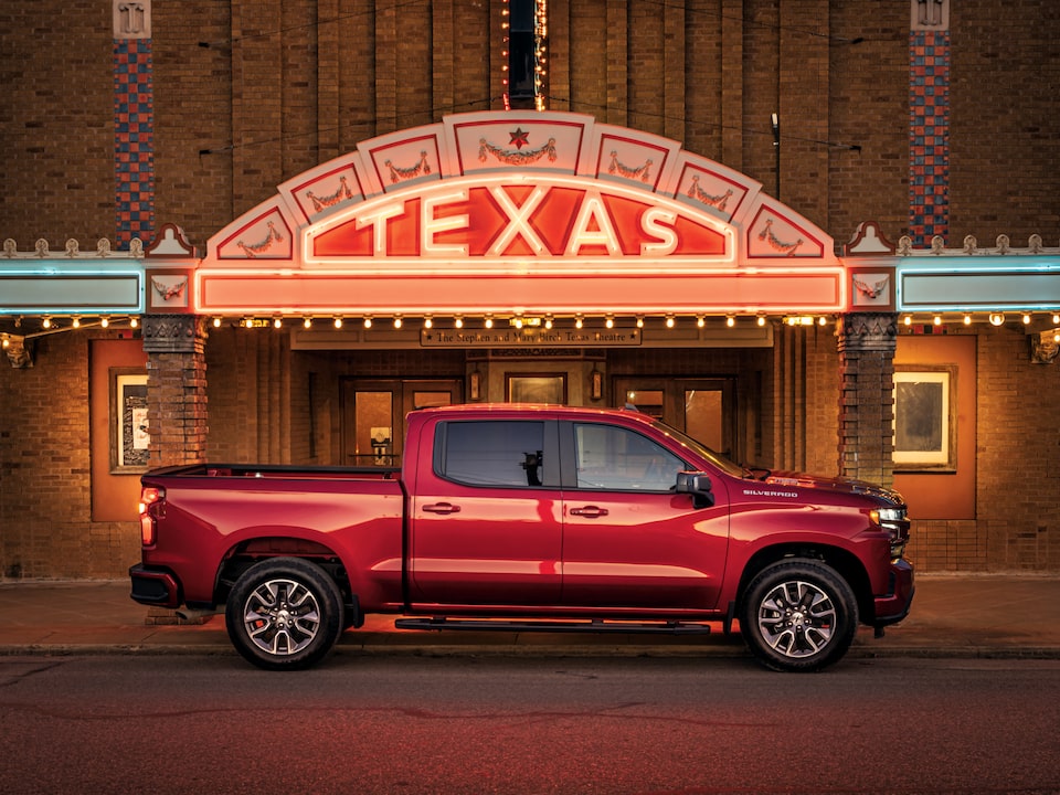 Una camioneta Silverado RST diesel roja frente a la marquesina iluminada del teatro Texas en Seguin.