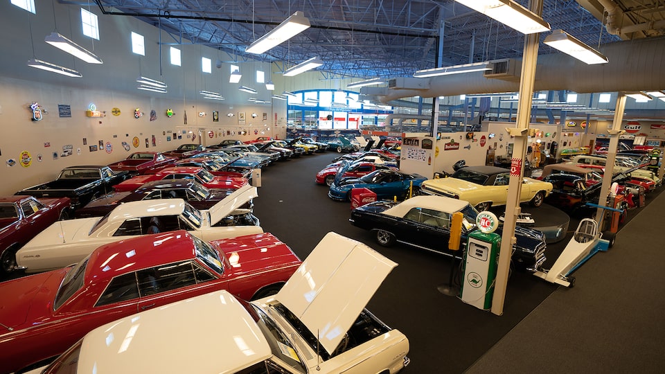 Una colección de vehículos adentro de Muscle Car City, que incluye un Impala antiguo y un Corvette contemporáneo.