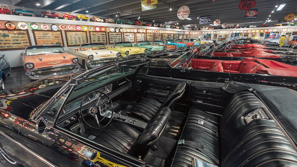 El interior color negro de un convertible color negro antiguo con los convertibles Chevrolet de los años 1950 en el fondo.