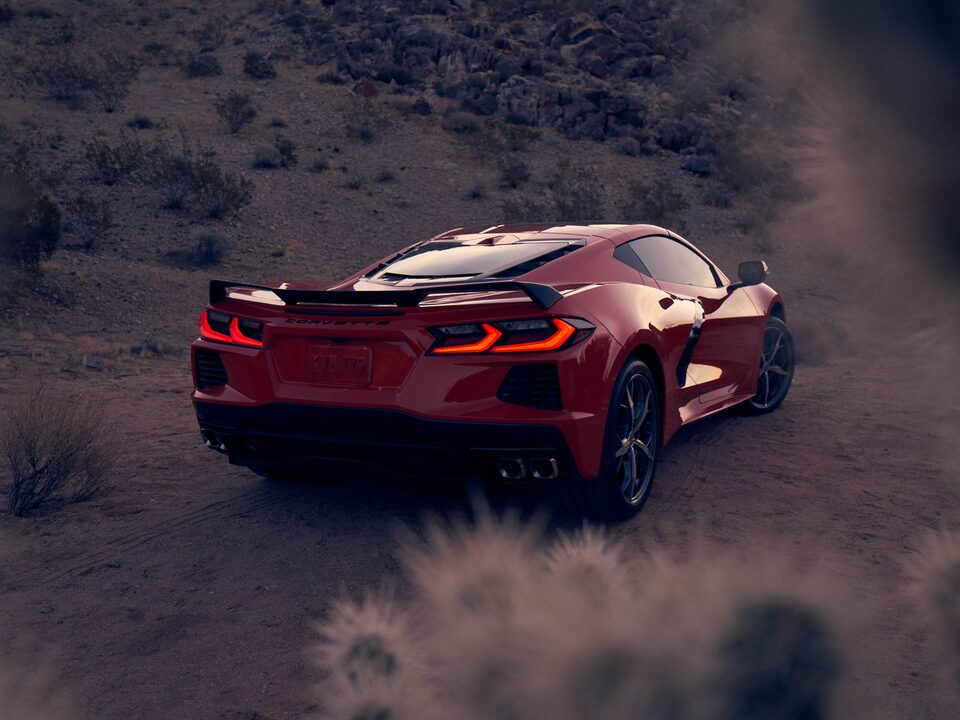 Un coupe Corvette 2020 en Rojo Antorcha en un paisaje desértico, visto desde atrás con las luces de freno encendidas.