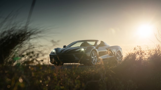 Silueta de un Corvette Convertible 2020 en Bronce Zeus Metálico en contraste con el sol poniente en un camino de la costa en Carolina del Sur.