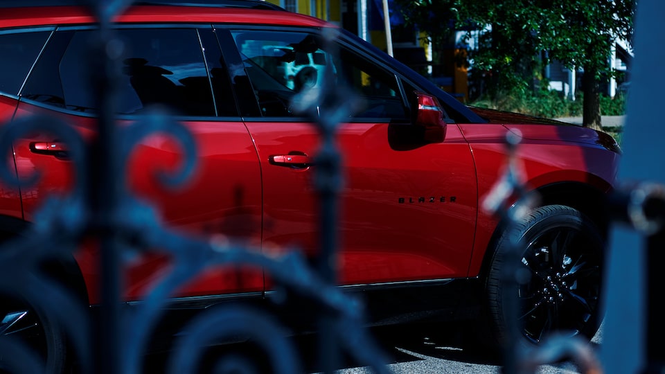 Vista de una Chevy Blazer roja a través de una puerta de hierro forjado.
