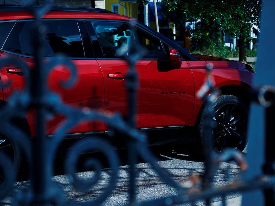 Vista de una Chevy Blazer roja a través de una puerta de hierro forjado.