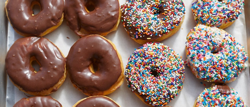 Una bandeja de donas cubiertas con glaseado de chocolate y chispas.