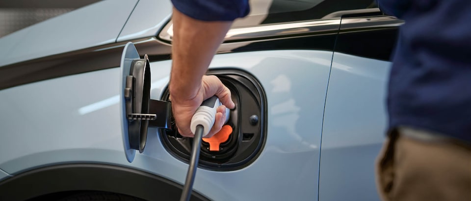 Primer plano de una persona enchufando un cable de carga en el puerto abierto de una Bolt EV.