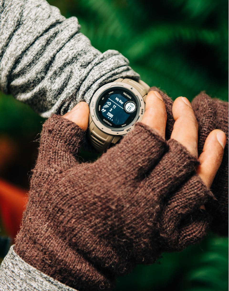 Someone’s forearms and hands are shown with a Garmin Instinct Smartwatch on their left wrist.