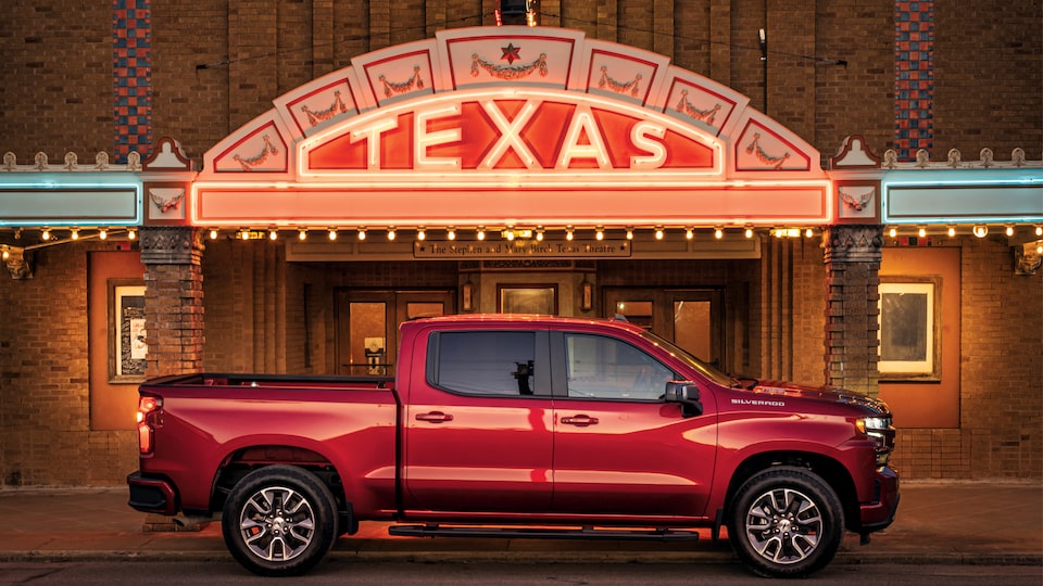 A red Chevy Silverado parked in front of the lighted marquee of the Texas Theatre in Seguin.
