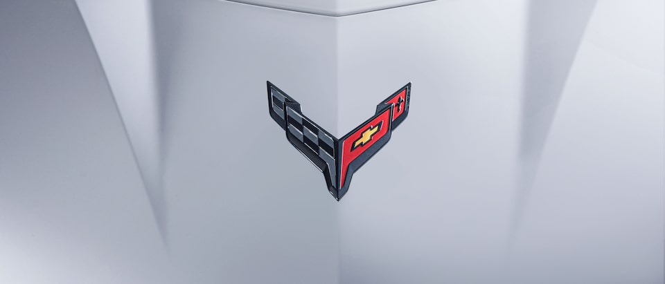 A closeup of the Corvette crossed-flags emblem on the hood of a white Corvette Z06.