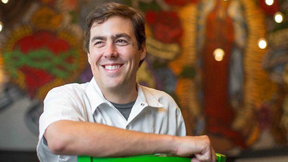 Chef Miles Landrem in front of a colorful wall mural at Landrem’s Mexican restaurant.