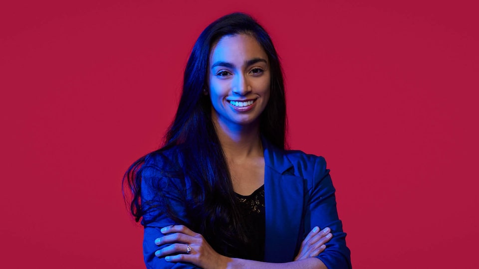 A head and shoulders shot of Kristine Pankow who’s smiling at the camera as she stands in front of a red background.