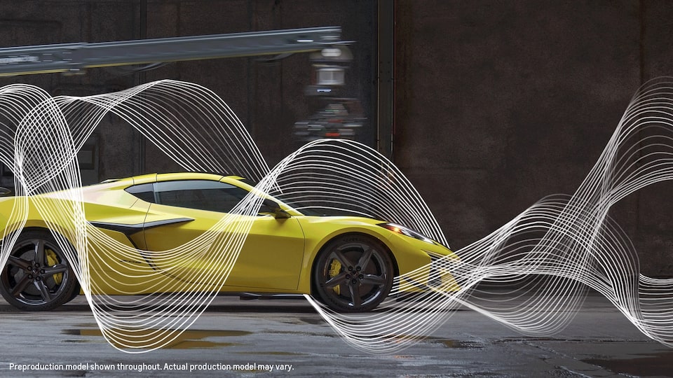 A yellow Corvette Z06 sits in a warehouse type of building in front of a dark background and brightly lit from the front. Illustrated sound waves weave around the car.