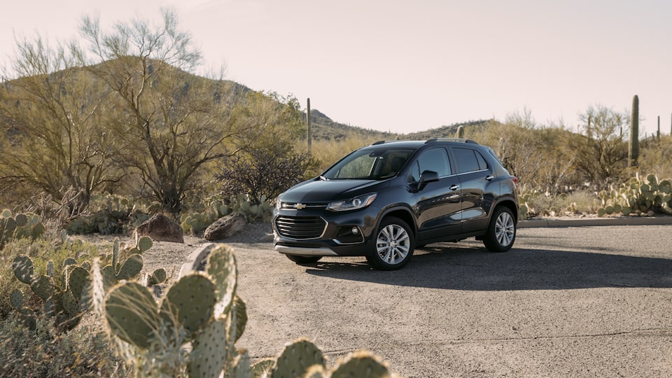 Trax, shown from the front driver’s side, parked near the desert hills and plants.
