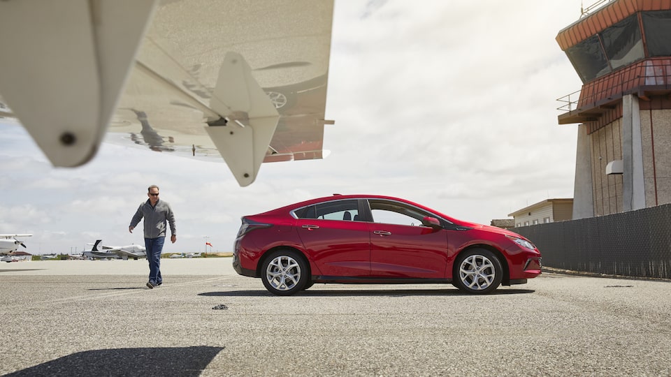  Entrepreneur Eli MurrayMetzger stands next to a Chevrolet Volt and an airplane.