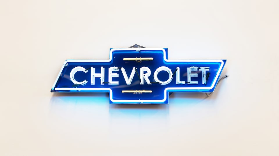 A vintage-style Chevrolet neon dealership sign, shaped like the bowtie logo with the word Chevrolet in the middle.