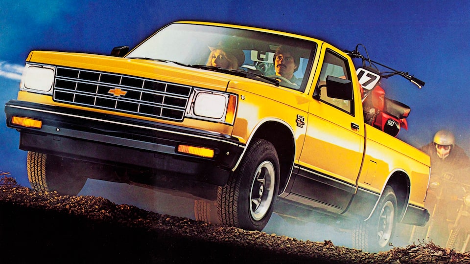 In a photo from the 1983 brochure, a 1983 two-tone Chevy S-10 pickup is seen from the back, showing the pickup bed filled with a stack of lumber and two barrels.