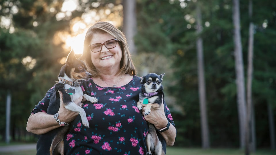 OnStar Member Teresa Moore, who was helped by OnStar after a severe crash, smiles as she holds her two small dogs.