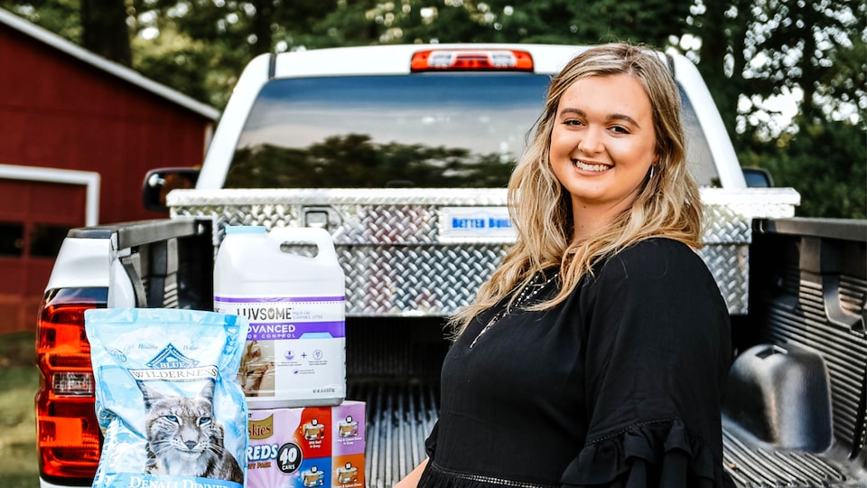 Scout Bagley stands at the open tailgate of her Silverado, which has several bags of pet food in the bed.