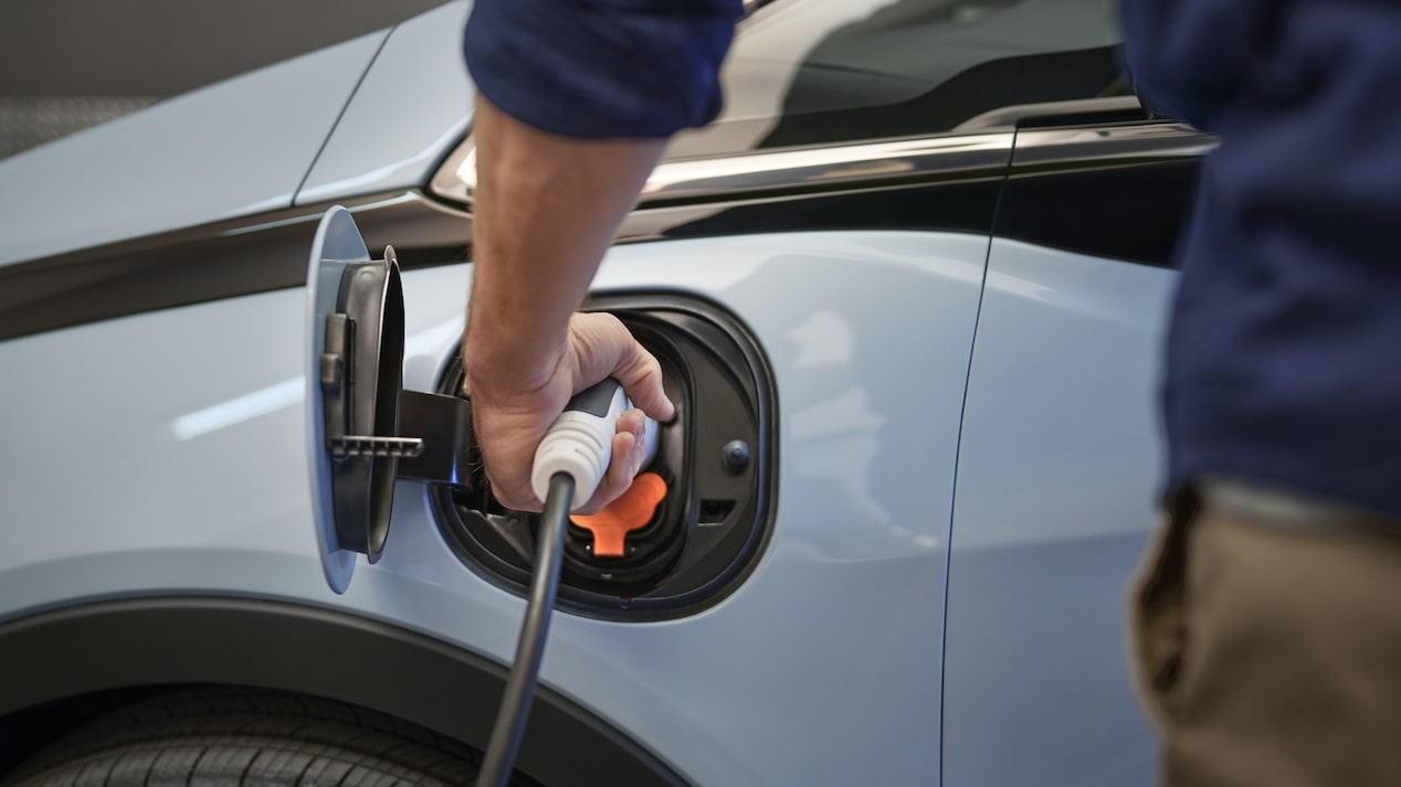 A close-up of a person plugging a charging cable into the open port on a Bolt EV.