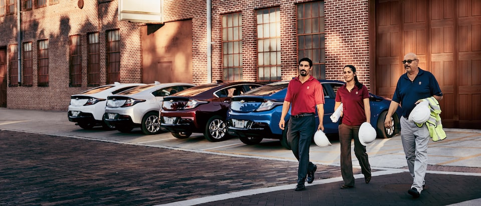Joe, Anna and Gregory Territo cross the parking lot in front of their fleet of Chevy Volts.