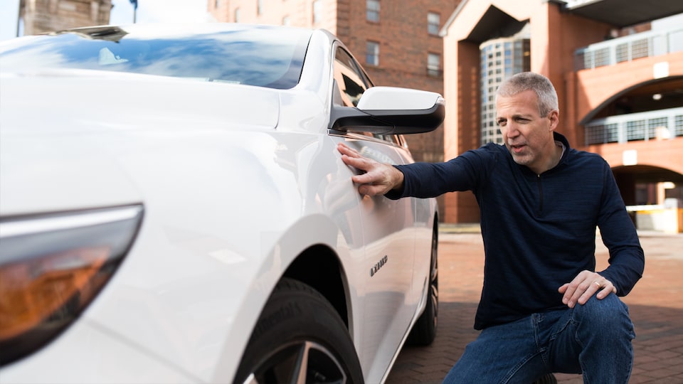 Mike Lucey crouching next to his Malibu to show off the design details.