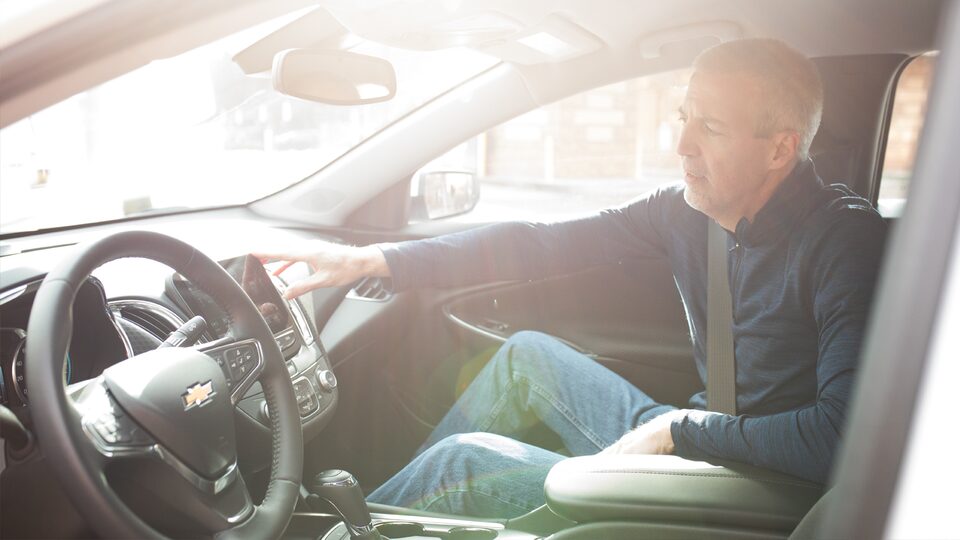 Mike Lucey pointing out interior details from the passenger seat of his Chevrolet Malibu.