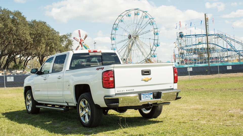 Una Chevy Silverado estacionada con la vuelta al mundo y la montaña rusa de fondo.