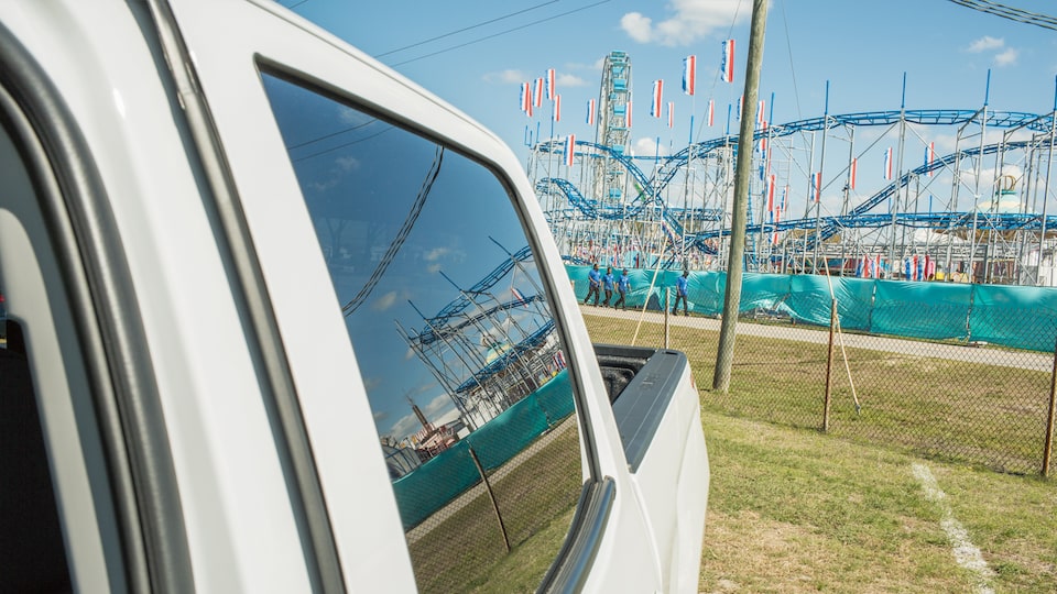 Una Chevy Silverado estacionada con una montaña rusa de la feria estatal en el fondo.