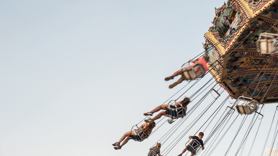 Asistentes a la feria estatal disfrutan de balancearse por el cielo de verano.