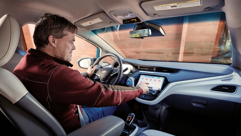 Ethan Stock at the wheel of his 2017 Chevy Bolt EV, using the touch screen.