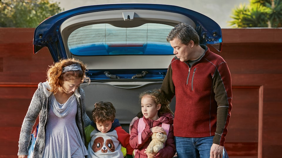 Ethan Stock with his wife and two kids standing at the back of their 2017 Chevy Bolt EV with the hatch open over their heads.