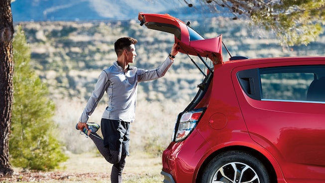 A man behind a Chevrolet Spark stretches before jogging.