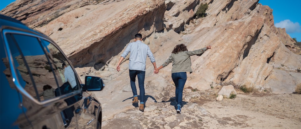 Una pareja tomada de las manos subiendo a una formación rocosa.
