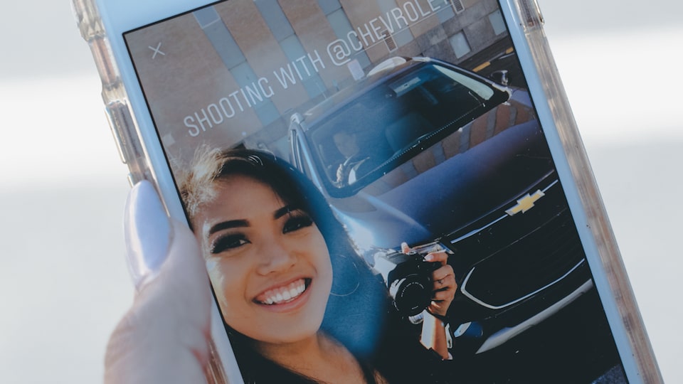 Mo Calderon's phone screen displays a self portrait in front of the Chevrolet Trax.