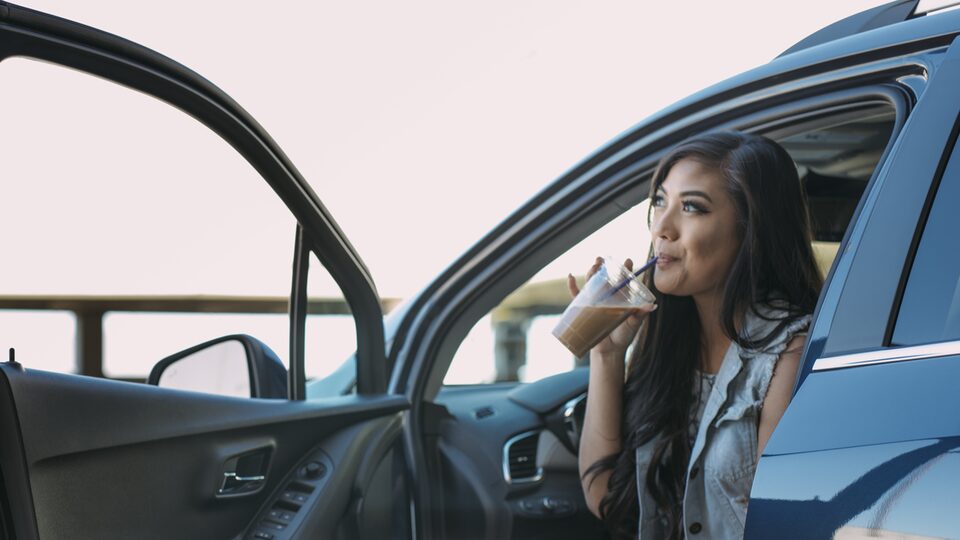 Vlogger Mo Calderon sips a cold coffee drink in the parked Chevrolet Trax.