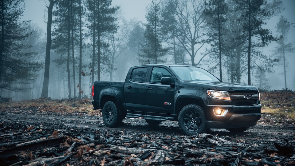 A 2018 Chevy Colorado Z71 Crew Cab Short Box with available Z71 Midnight Edition package, sitting in a foggy, wooded area.