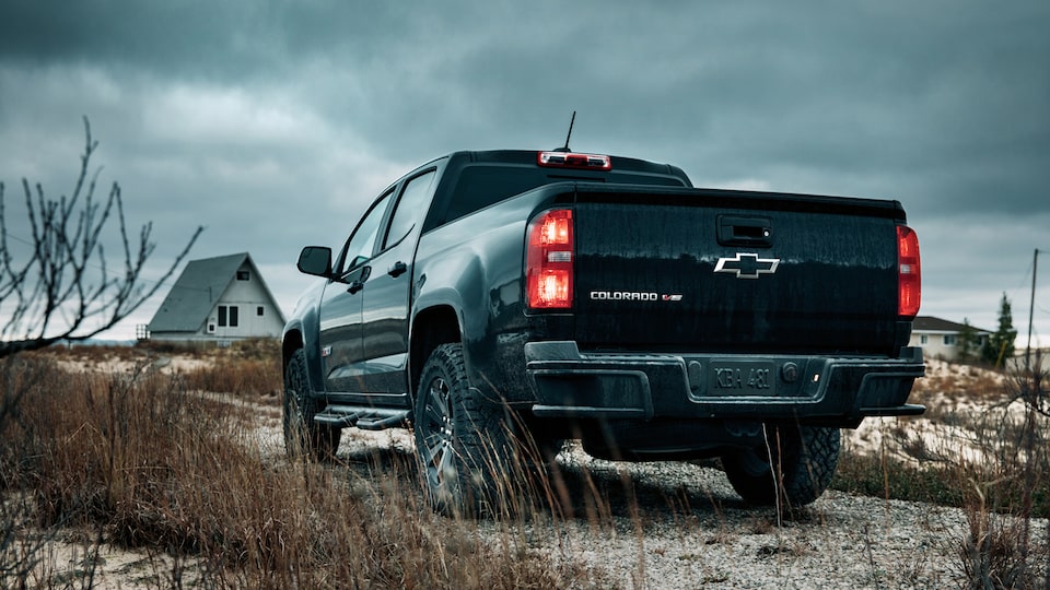 The back of a black 2018 Chevy Colorado Z71 Crew Cab Midnight Edition sitting in gravel near a Lake Michigan beach.