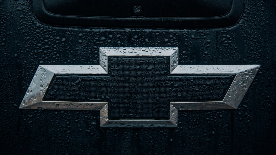 The black and silver Chevrolet bowtie logo spattered with rain on the back of the Colorado Z71 Crew Cab Midnight Edition.