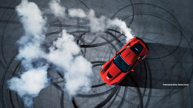 Toma cenital de un Corvette rojo haciendo giros en una pista cerrada.