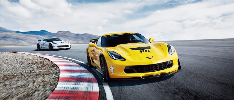 Un Corvette color amarillo y uno color blanco en la pista.